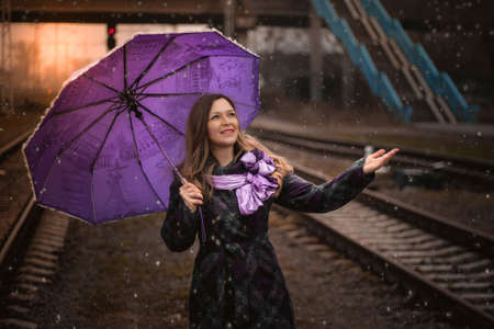 Woman with umbrella standing on the platform of a train stationの写真素材