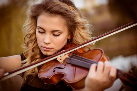 Young woman playing the violin at park. Shallow depth of field.の写真素材