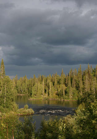 The river Krasnenkaja on Kola peninsula Russia. In the middle of the river a small threshold with raging water, around woodの写真素材