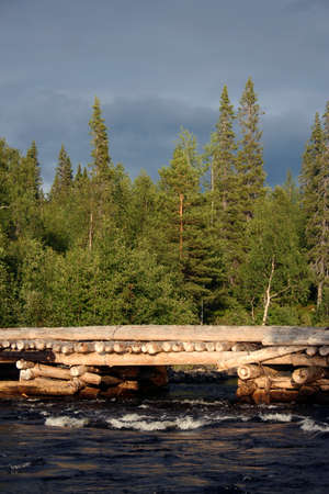 Old wooden bridge over river in Russian forest
