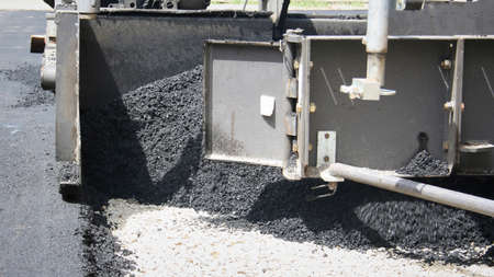 Industrial pavement truck laying fresh asphalt on construction site