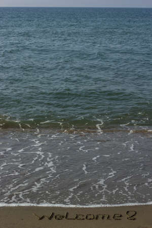 Welcome written in a sandy beachの写真素材