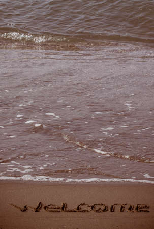 Welcome written in a sandy beachの写真素材