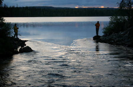 Men fishing in lake at sunsetの写真素材
