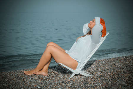 Woman in santa hat sitting on the beachの写真素材