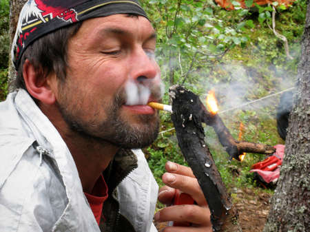 LUTSK, UKRAINE - AUGUST 09 - Man lights a cigarette from firebrand in Lutsk on August 09, 2008.のeditorial素材