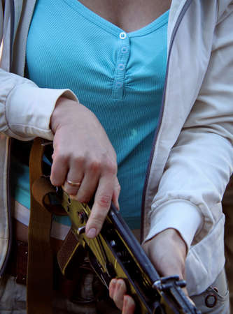 Female hand harvested rifle AK-47. Shallow depth of field.