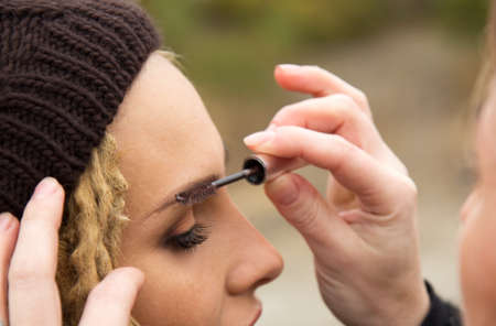 Make up artist at work, correcting eye lashes preparing caucasian model with a dreadlocks hairstyle to wedding photo sessionの写真素材