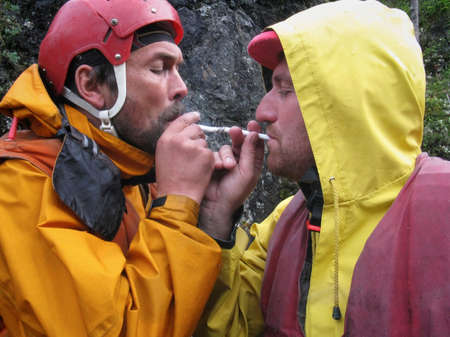 LUTSK, UKRAINE - AUGUST 09 - Two men wearing helmet lights smoking cigarette near rock in Lutsk on...