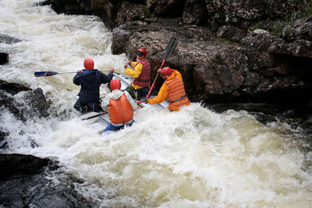 KOLA PENINSULA, RUSSIA - AUGUST 11 - Team of men on an inflatable catamaran at rough river in Kola...