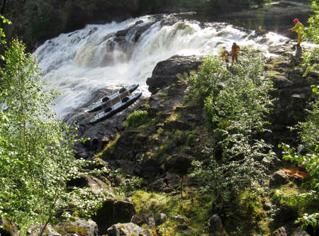 KOLA PENINSULA, RUSSIA - AUGUST 12 - Men transfer inflatable catamaran on land because dangerous waterfall in Kola Peninsula on August 12, 2008.のeditorial素材