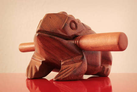 Wooden sculpture of frog on red mirror surface. Shallow depth of field.の写真素材