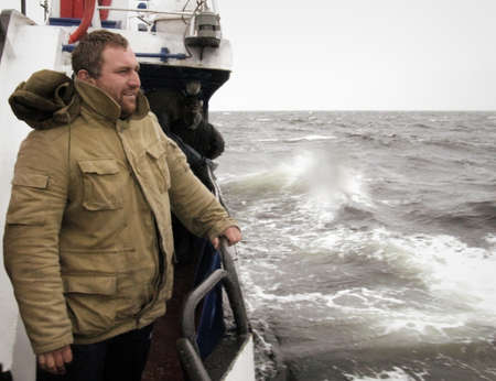 WHITE SEA, RUSSIA -19 AUGUST 2008: Man on boat desk against storm seaのeditorial素材