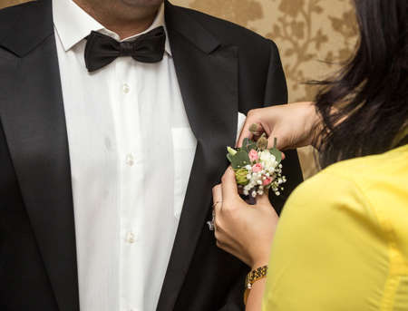 Woman put on wedding boutonniere on grooms jacketの写真素材