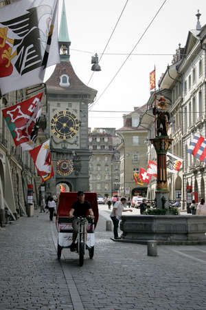 BERN, SWITZERLAND - 03 May 2009: Local tourist taxi on the street Kramgasse with fountain and clock tower in the old town. It is a popular shopping street and medieval city centerのeditorial素材