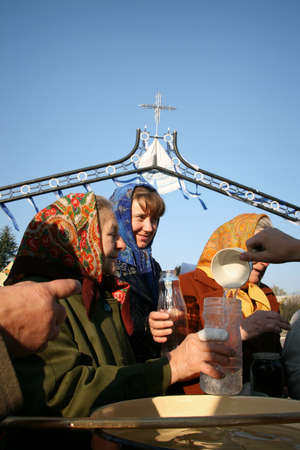 VOYUTYN, UKRAINE - 14 OCTOBER 2008: Unidentified women take holy water during the religious...