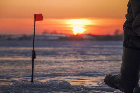 Fisherman on a lake at winter sunsetの写真素材