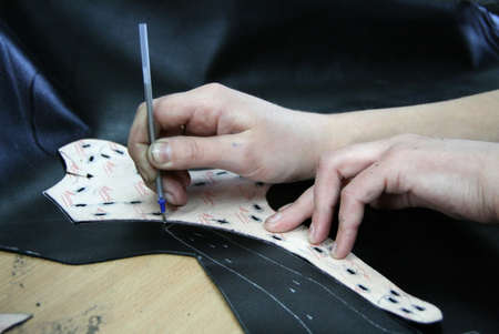 VYSHNIVEC, UKRAINE - 12 November 2008: Tailor hands measuring a piece of leather  in rural workshop,...