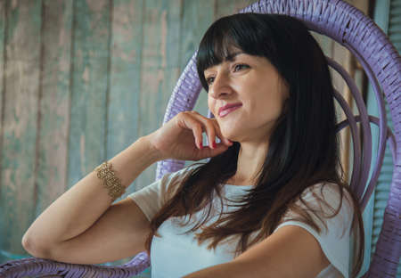 Portrait of a brunette caucasian woman relaxing on rattan rocking chairの写真素材