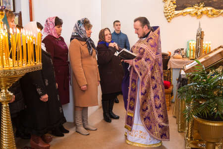 VOYUTYN, UKRAINE - 11 March 2017: Orthodox priest and church parishioners during holiday prayers