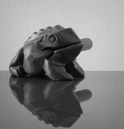 Wooden sculpture of frog on red surfeの写真素材