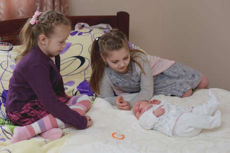 LUTSK, UKRAINE - 26 March 2017: Happy laughing girls and his sleeping newborn baby sisterのeditorial素材