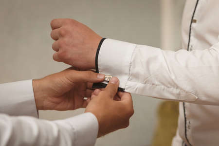 Groomsman helps to groom to put on cufflinks