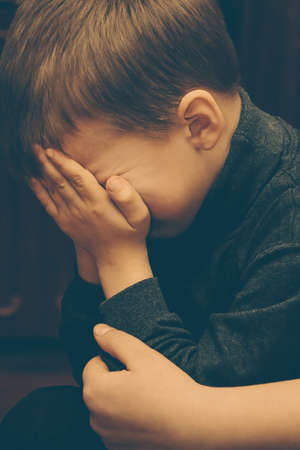 POLYCI, UKRAINE - 27 January 2009: Sad little boy closed face with his hands at homeのeditorial素材