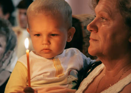 KIVERCI, UKRAINE - 26 July 2009: Senior woman and little blond caucasian boy with candles in Orthodox Ukrainian Churchのeditorial素材