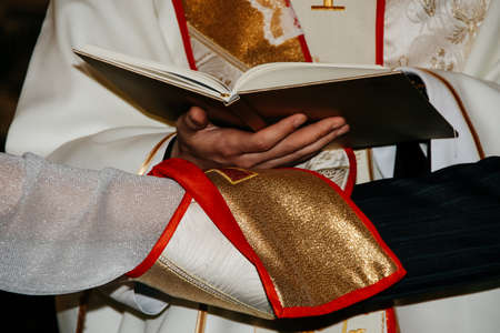 Priest holding bible above hands of bride and groom during wedding ceremony in christian churchのeditorial素材