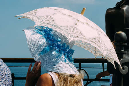 Woman in hat walking on pier with umbrella at sunny dayの写真素材