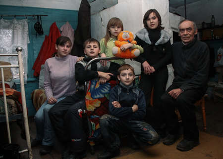 ADAMIVKA, UKRAINE - 26 January 2009: Father with children sit on the bed and posing  in the room of the country houseのeditorial素材