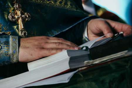 Hands of priest on the Bible. Shallow depth of fielf.