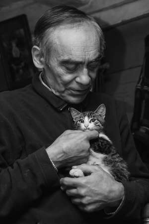 ADAMIVKA, UKRAINE - 26 January 2009: A man playing with kittens in a country houseのeditorial素材