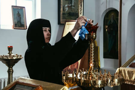 STAROSILLIA, UKRAINE - 4 February 2009: Unknown nun cleans the candlestick in the church
