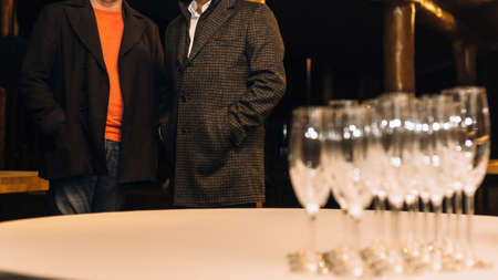 Two men and empty glasses for wine on table at outdoor restaurant. Shallow depth of field.