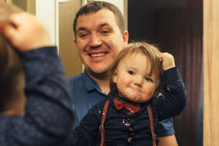 Reflection in mirror of dirty child and funny fatherの写真素材