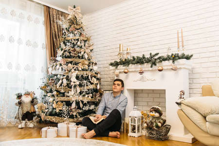 Caucasian teenage boy with book at Christmas in homeの写真素材