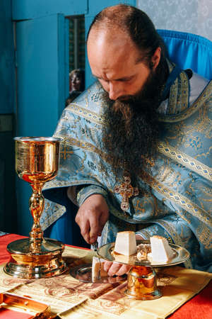 Voyutyn, Volyn / UKRAINE - October 14 2014: Priest consecrates bread during orthodox liturgy ceremonyのeditorial素材