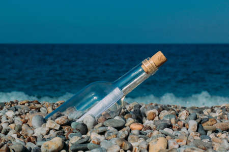 Rolled letter inside glass bottle on a beachの写真素材