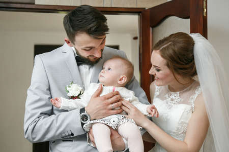 Cuman, Volyn / Ukraine - April 29 2018: Happy wedding couple with little baby posing on their wedding day at restaurantのeditorial素材
