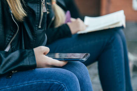 Girls using smart phone and reading the book.の写真素材