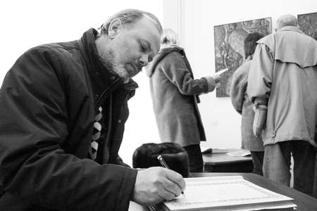 Zbarag, Ternopil / Ukraine - February 20 2009: Man writes response in a book at exhibitionのeditorial素材