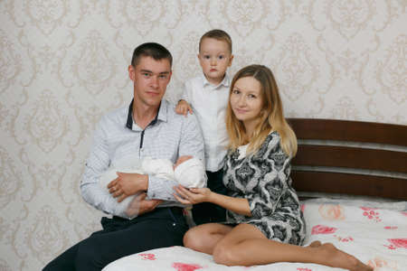 Happy young parents with two children in the bed at homeの写真素材