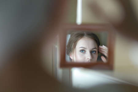 Gentle young bride looks in the mirrorの写真素材