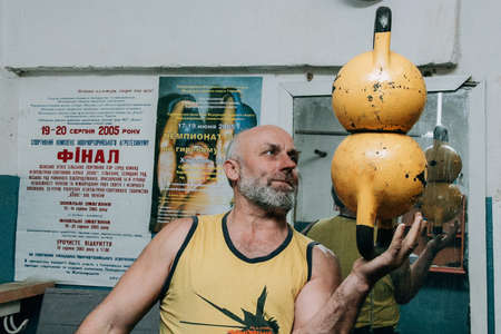 Novograd, Volyn / Ukraine - March 31 2009: Senior man working out using kettlebell in rural gymのeditorial素材
