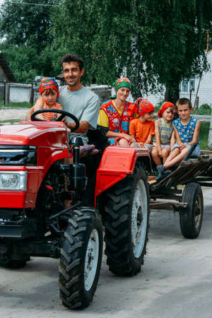MULCHYCI, Rivne / UKRAINE - JUNE 22 2011: Young farmer and his family on a tractor