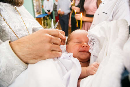 Volodymyr, Volyn / Ukraine - September 09 2018: The priest cuts the baby at baptism. Shallow depth of field.のeditorial素材