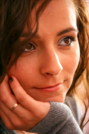 Young woman in sweater holding her chin, looking aside