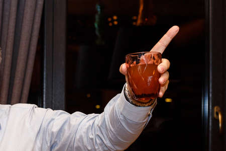 Elegant man holds glass of juice, showing forefinger gesture